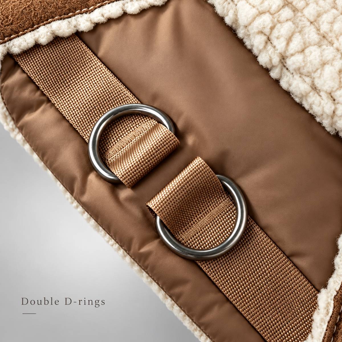 Double D-rings on brown webbing with cream sherpa trim nearby.