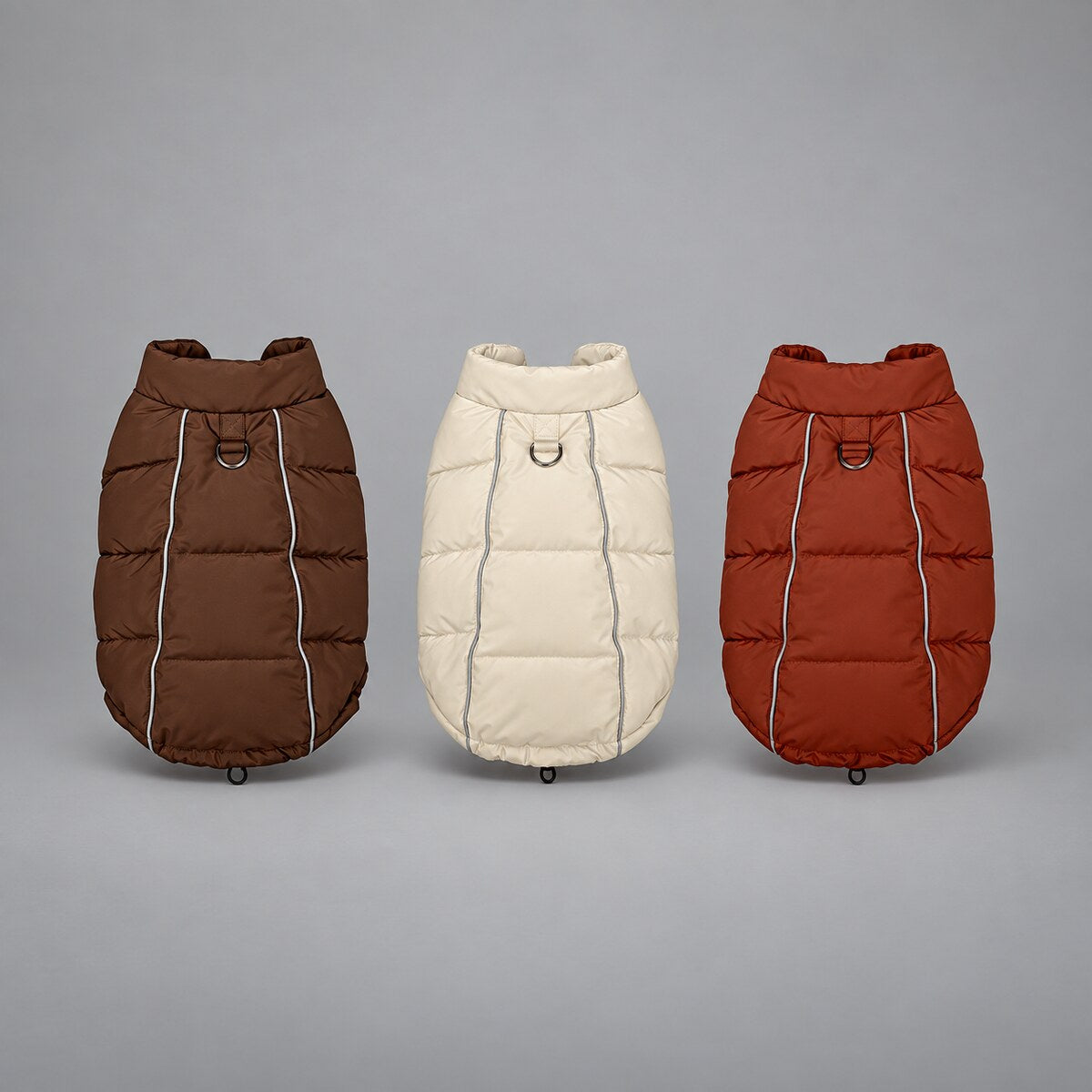 Winter dog puffer vests in Mocha Brown, Soft Beige and Brick Red, shown together from the back.