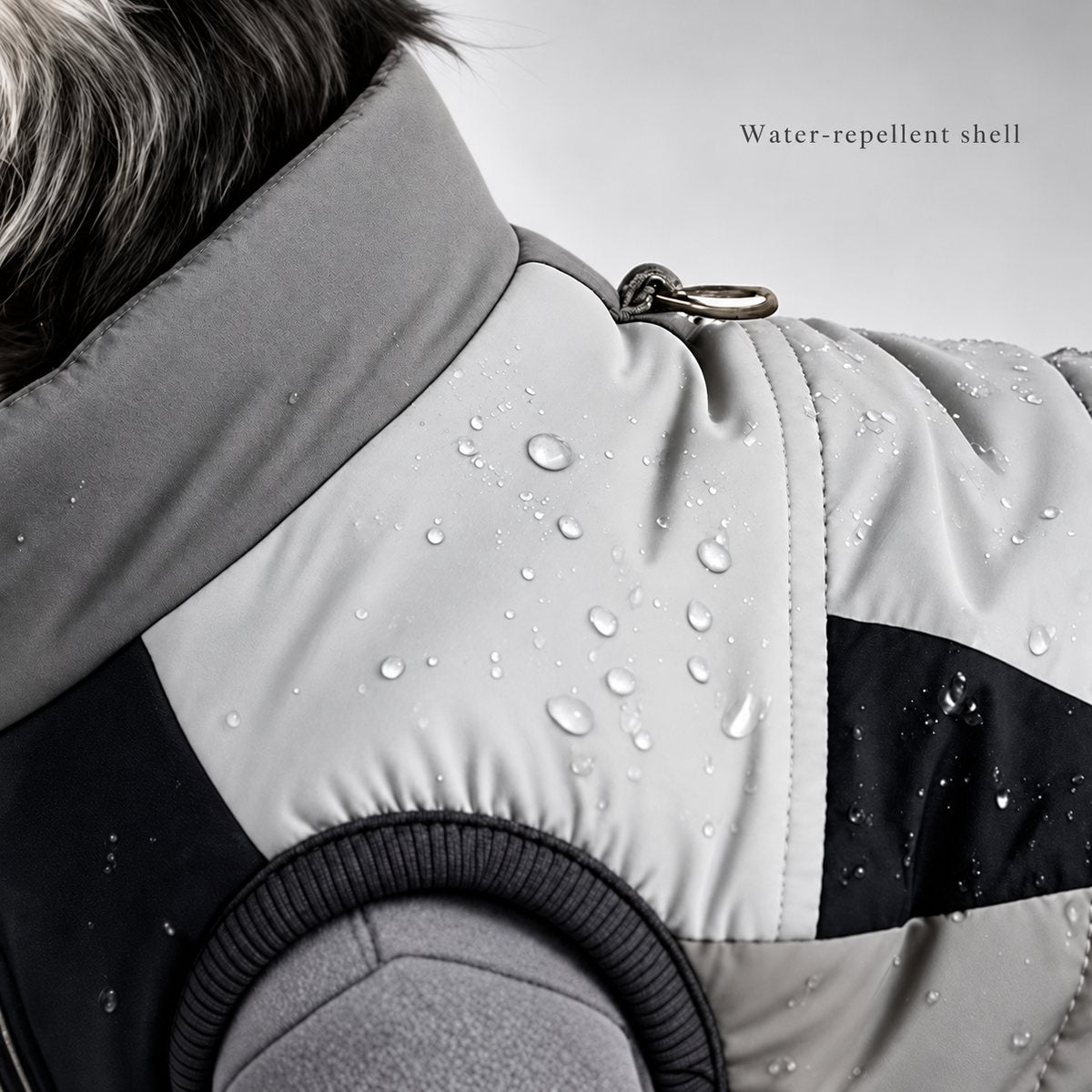 Close-up of water droplets on the gray and black vest shell beside the back D-ring.