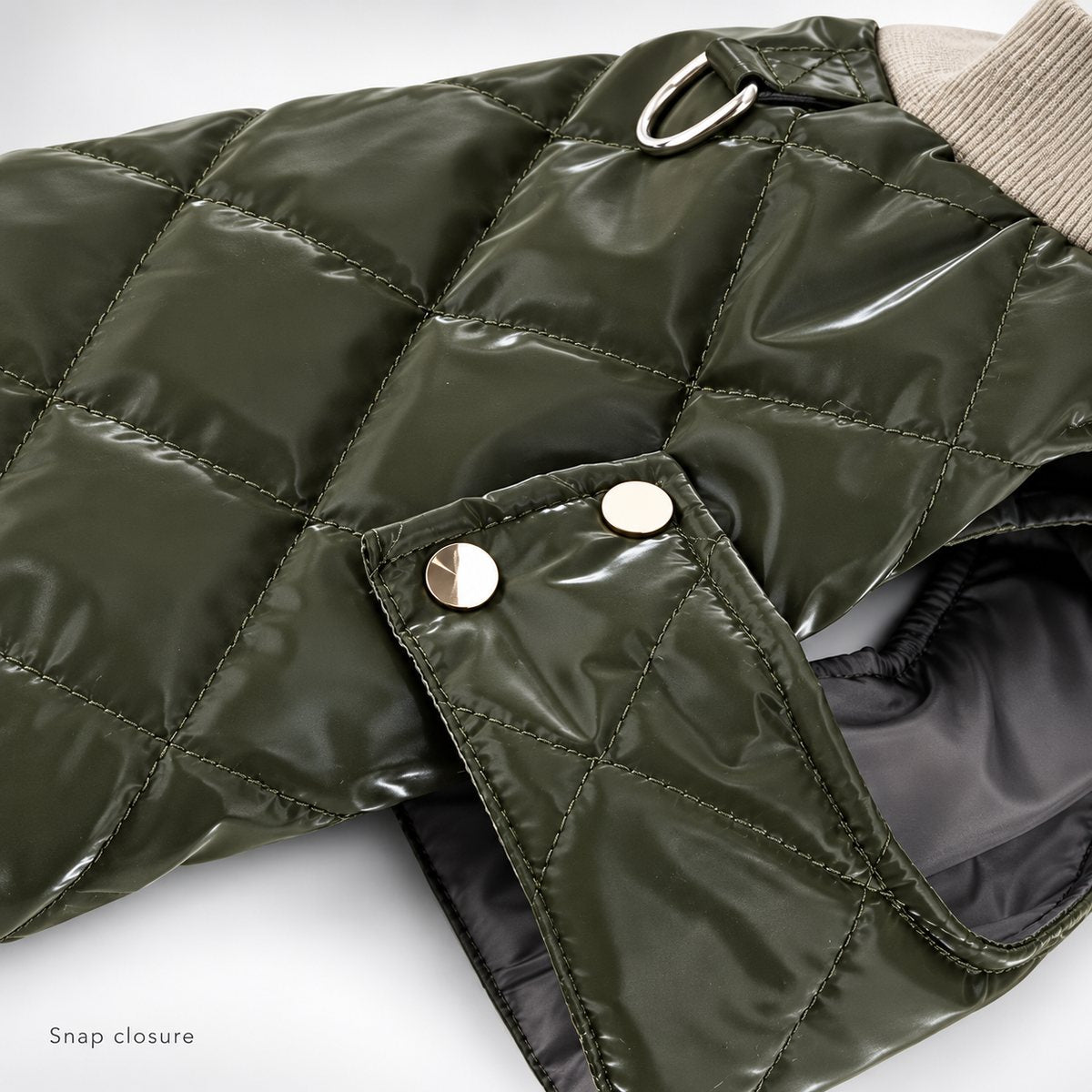 Olive quilted side tab with two gold-tone snap fastenings beside the bound arm opening.