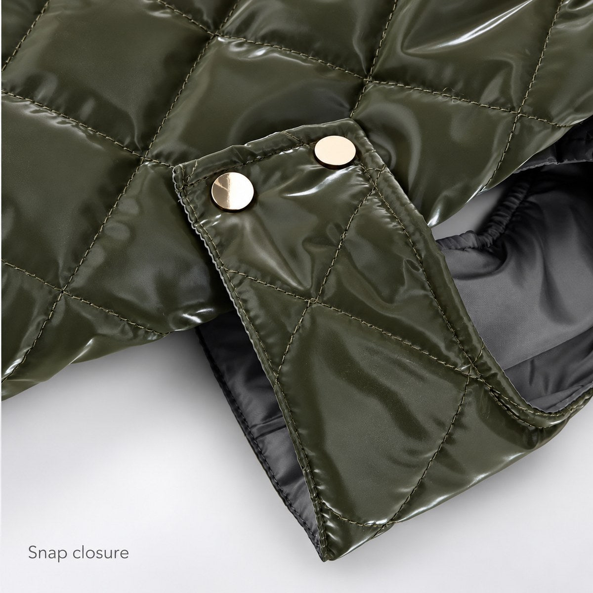 Close-up of the closed side snap tab and stitching on the olive faux leather vest.