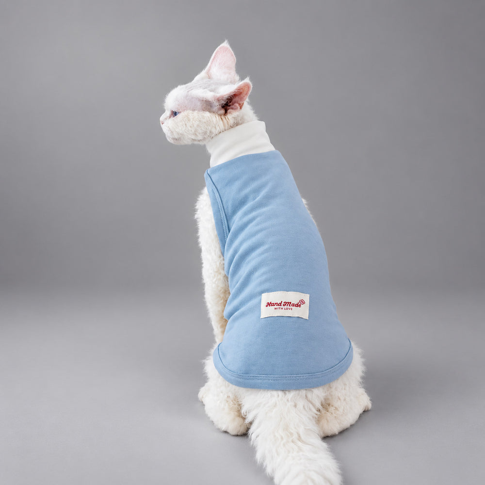 Cat wearing the Light Blue Powder Cloud vest, seated in rear view.