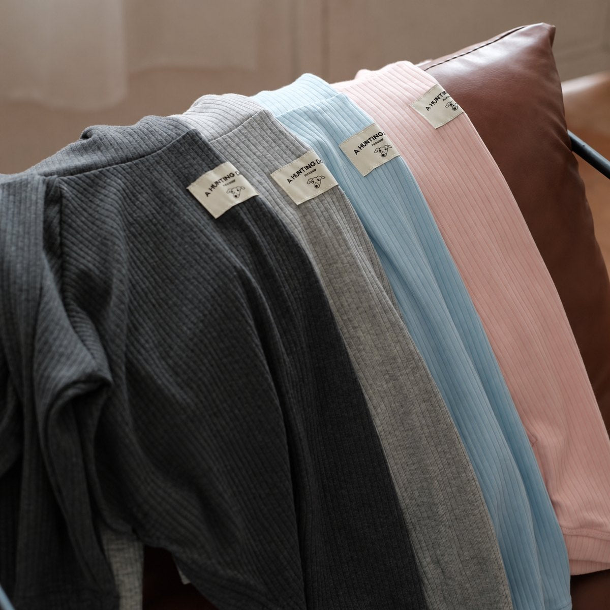 Close-up of ribbed turtlenecks in charcoal gray, heather gray, ivory, baby blue and light pink.