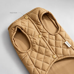 Close-up of the tan quilted vest showing its snap fastenings and bound arm openings.